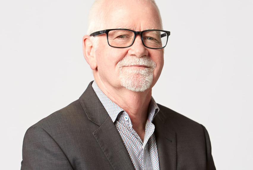 A professional man in a suit jacket and glasses, showcasing a polished and sophisticated appearance.