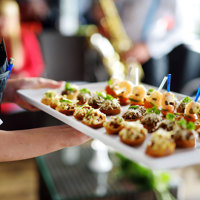 A person holding a tray of nicely prepared foods