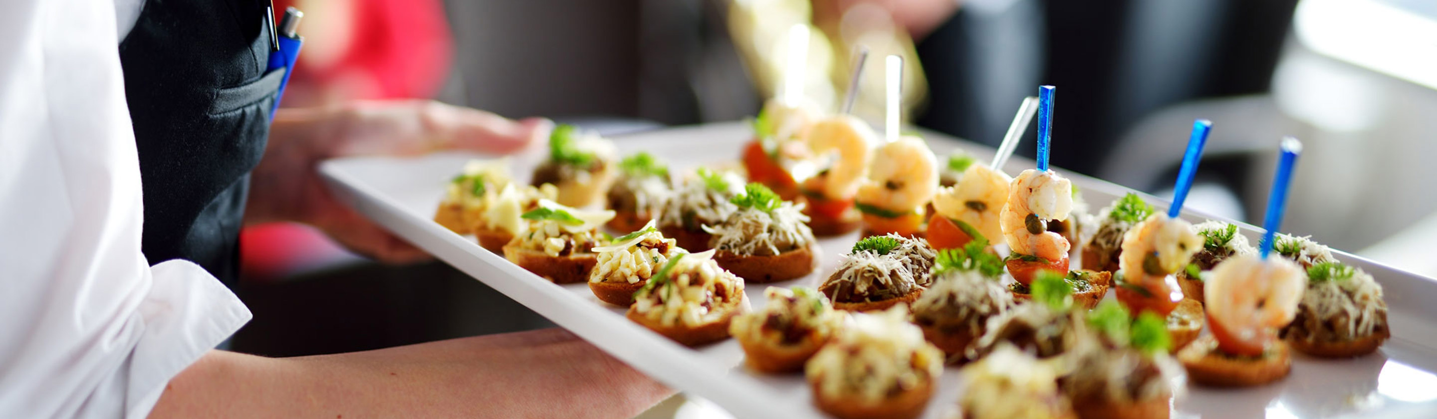 A person holding a tray of nicely prepared foods