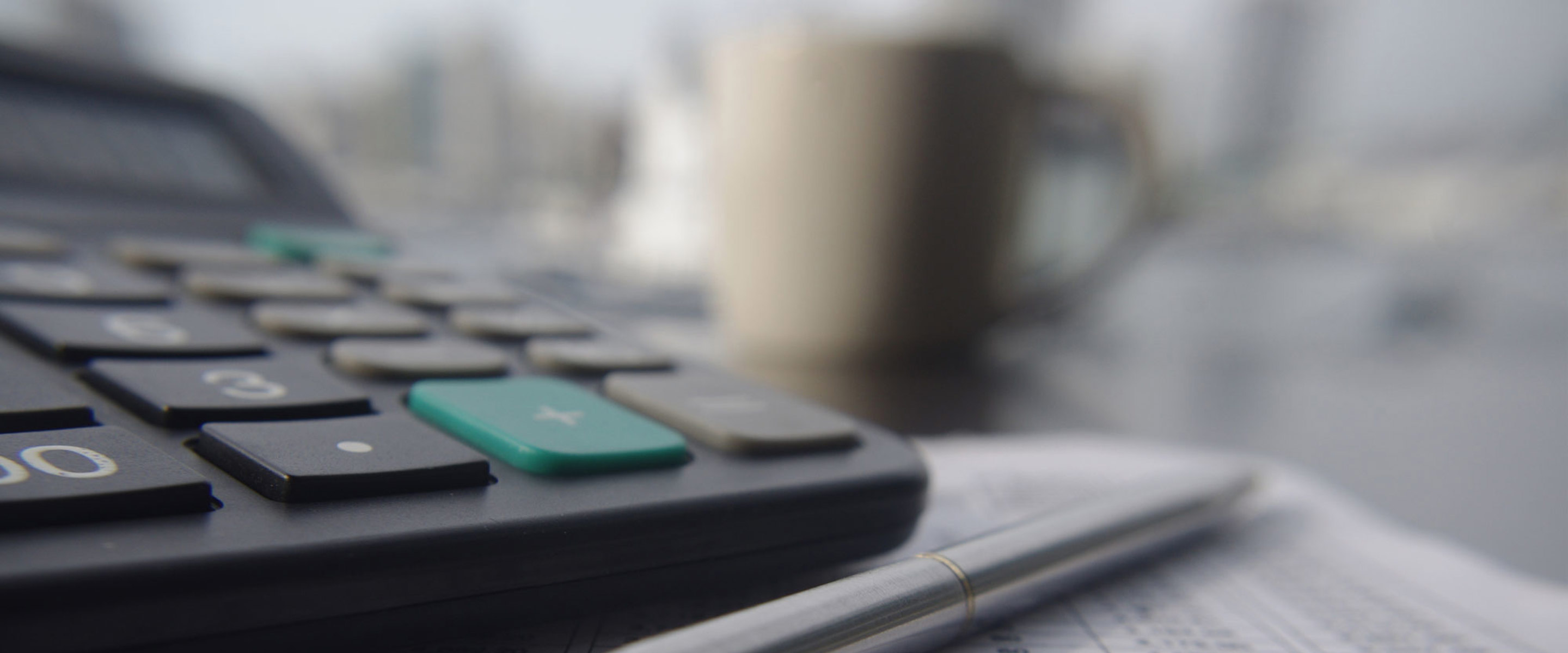 A pen and calculator on a desk, sitting on top of written calculations