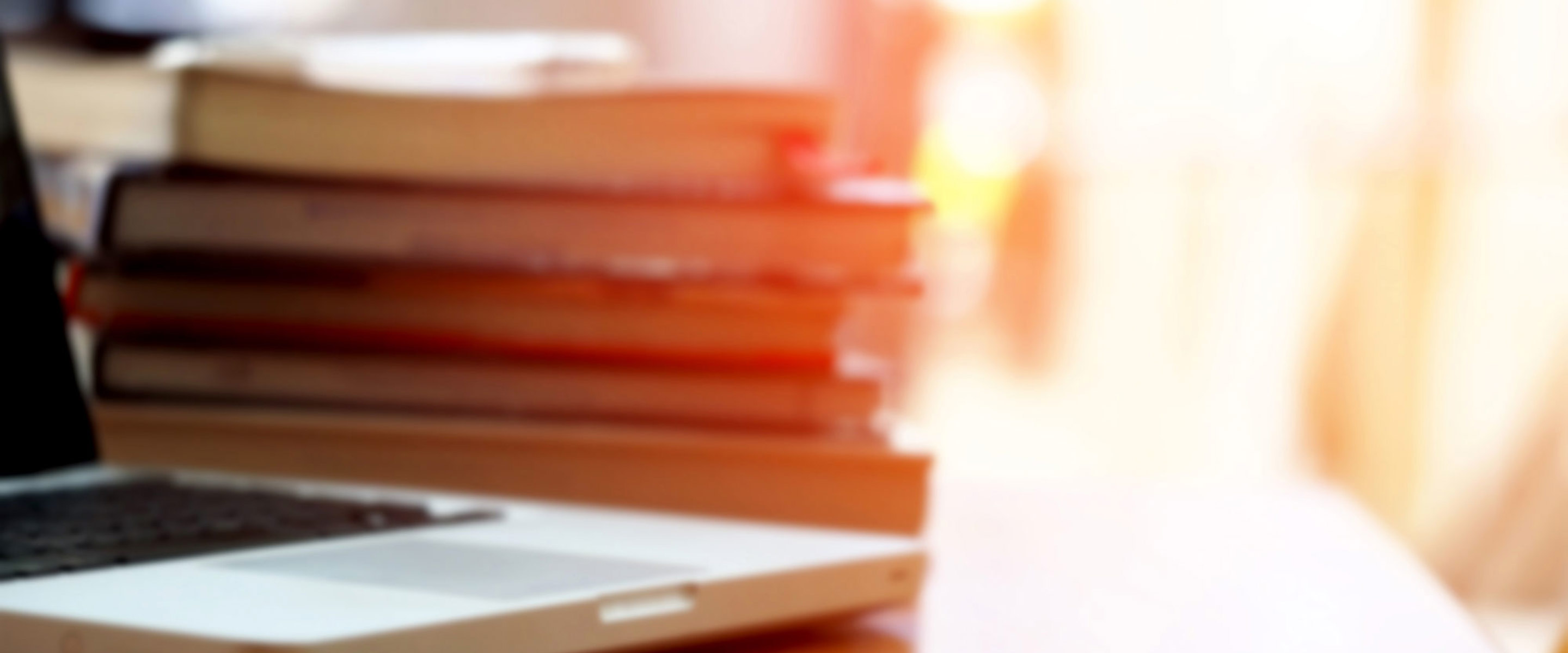 A laptop sitting on a desk with books next to it