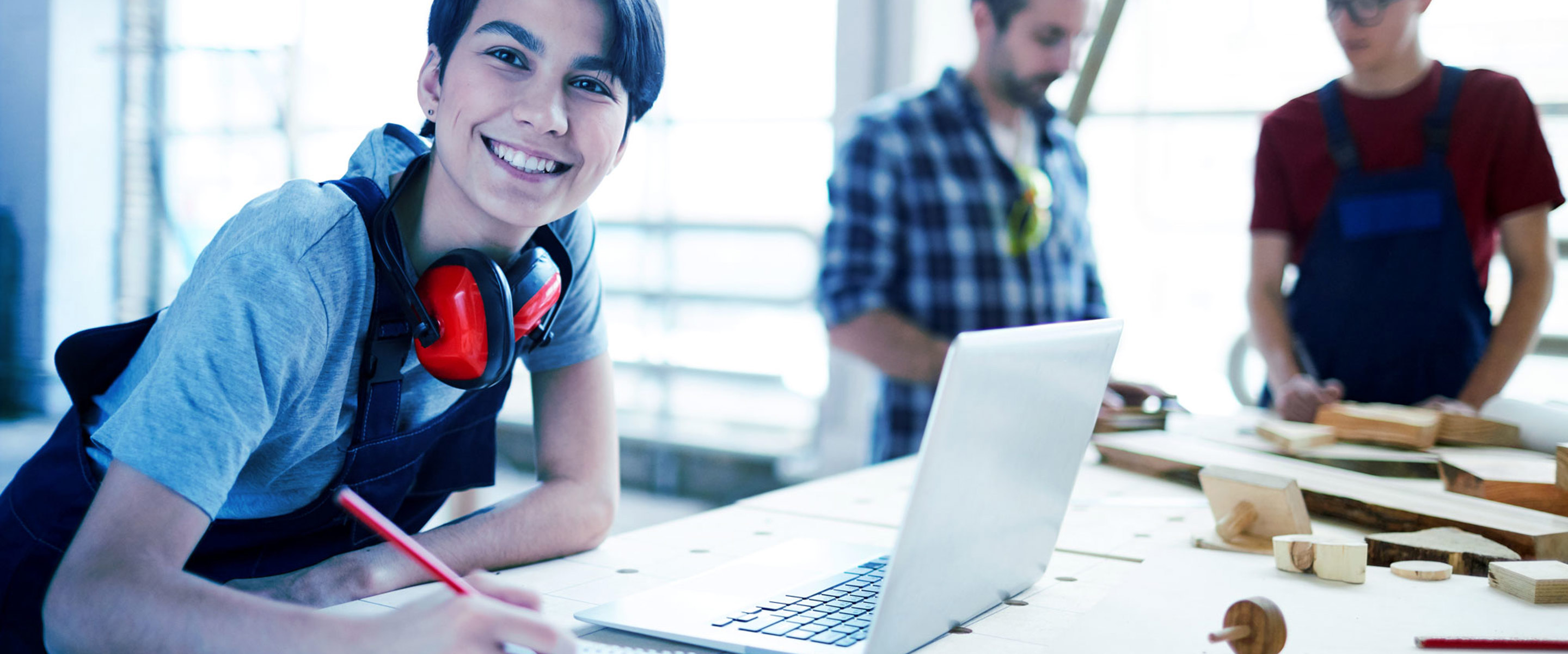 A person smiling at the camera whilst using a laptop