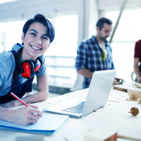 A person smiling at the camera whilst using a laptop