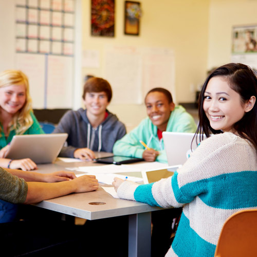 A group of students sitting around a table with laptops and paperwork 