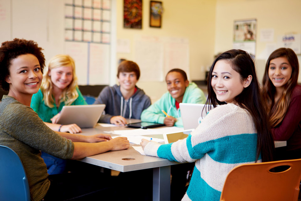 A group of students sitting around a table with laptops and paperwork 