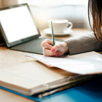 A person taking notes from a laptop