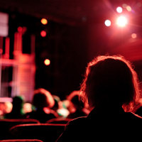 A person sitting back and watching a performance on a stage