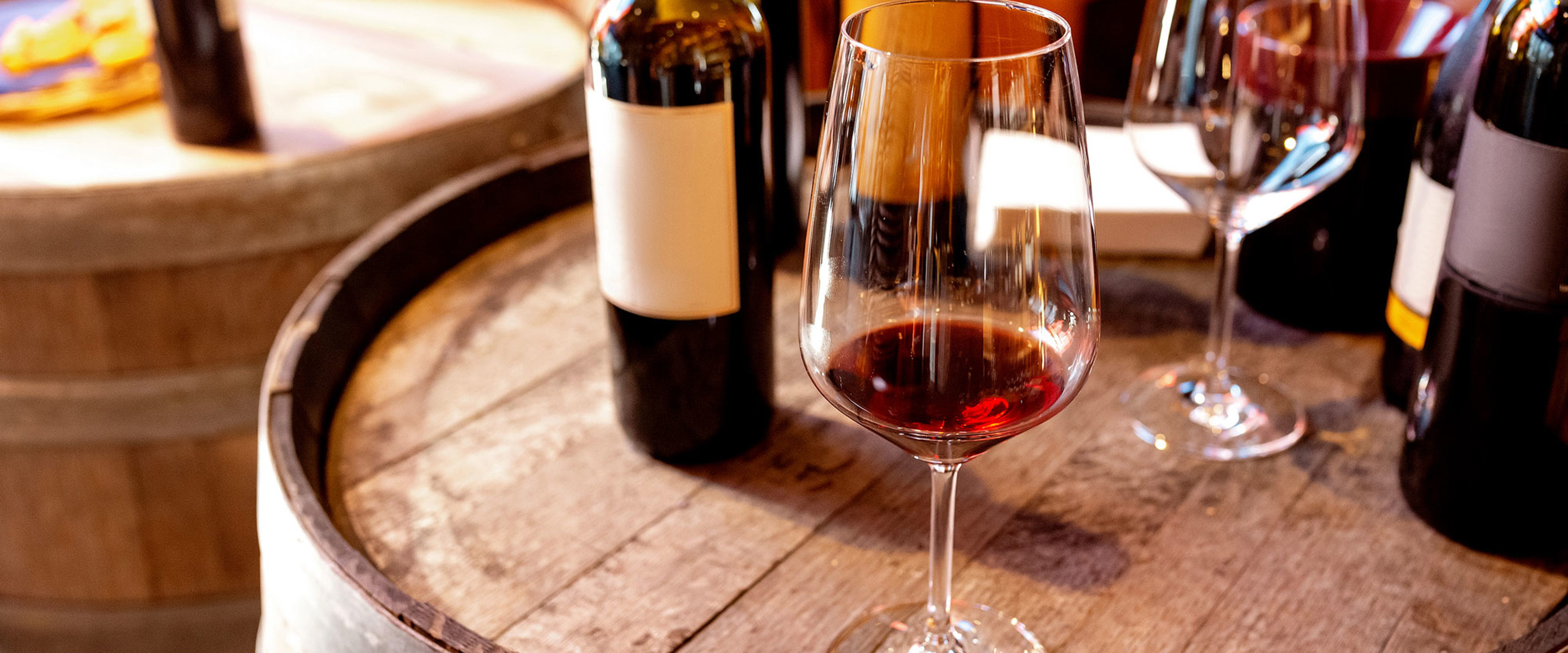 Glasses and bottles of wine sitting on a barrel