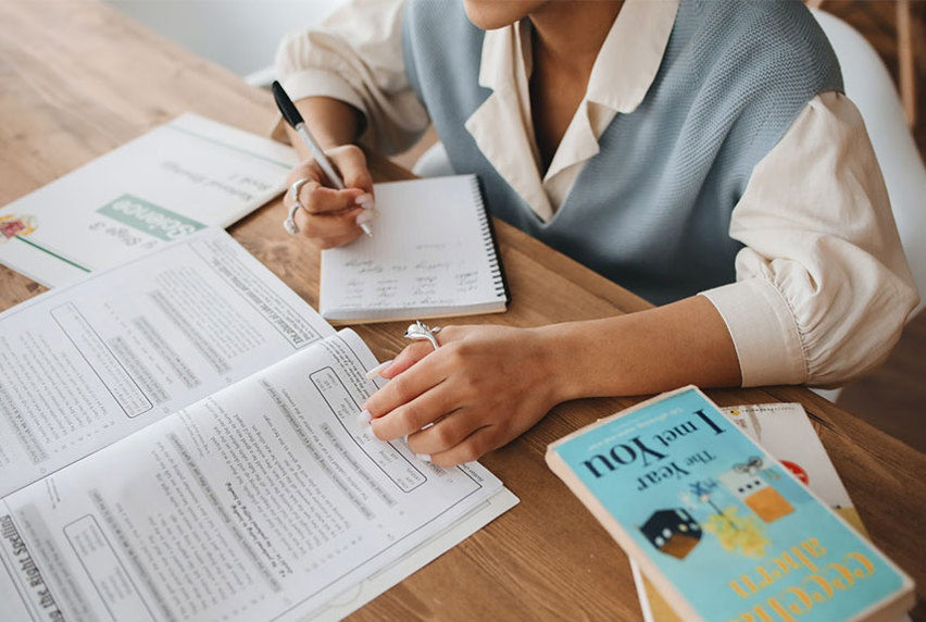 Student is studying at their desk with notebooks around them 