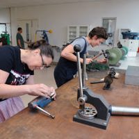 Two jewellery students working with items in vices in the jewellery workshop