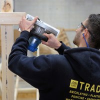 Building Surveying and Construction student with using a hand saw on a timber frame