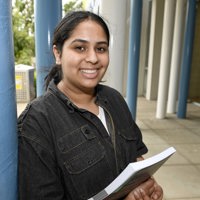 Community Services student leaning against a pole outside a building on Melbourne Polytechnic campus