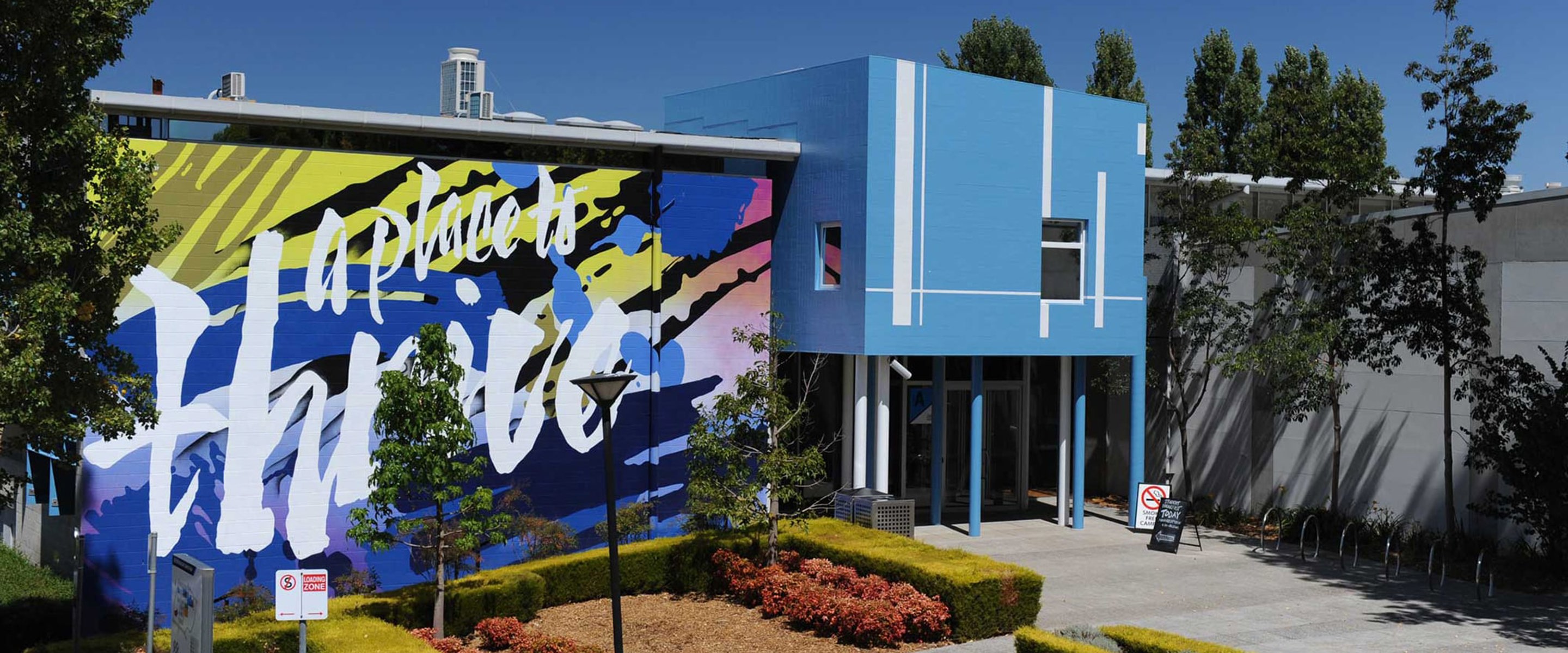 A blue building with a large mural that says "a place to thrive".