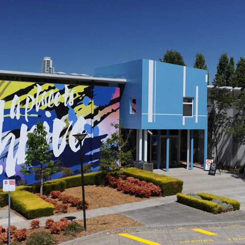 A blue building with a large mural that says "a place to thrive".