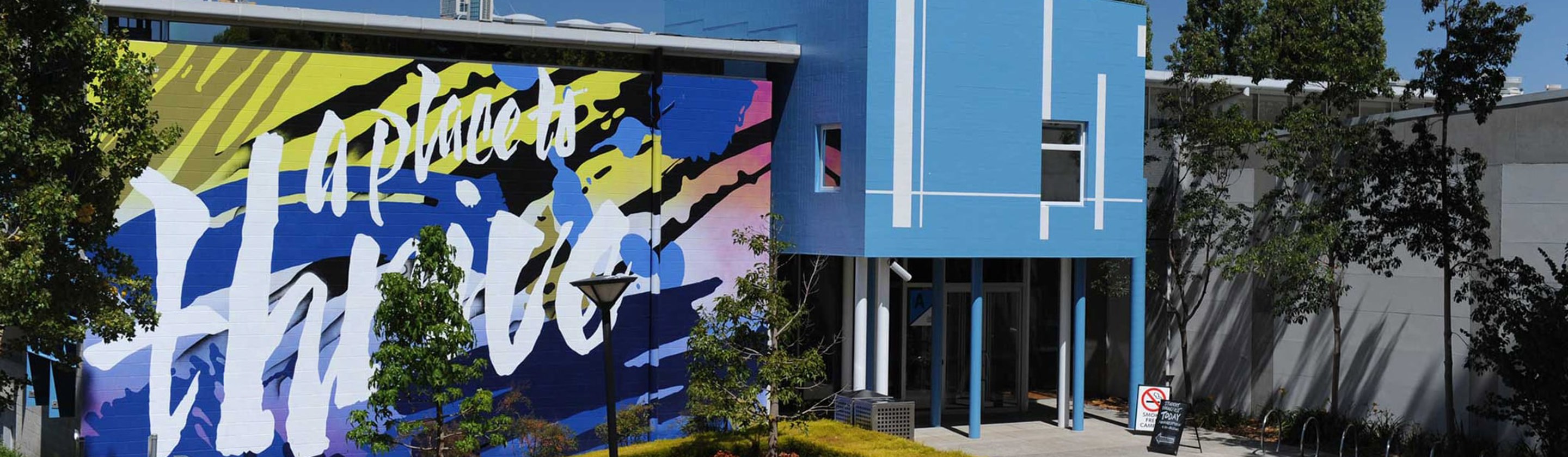 A blue building with a large mural that says "a place to thrive".