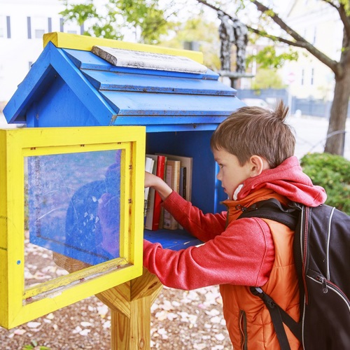 Image of child exchanging books at street library box