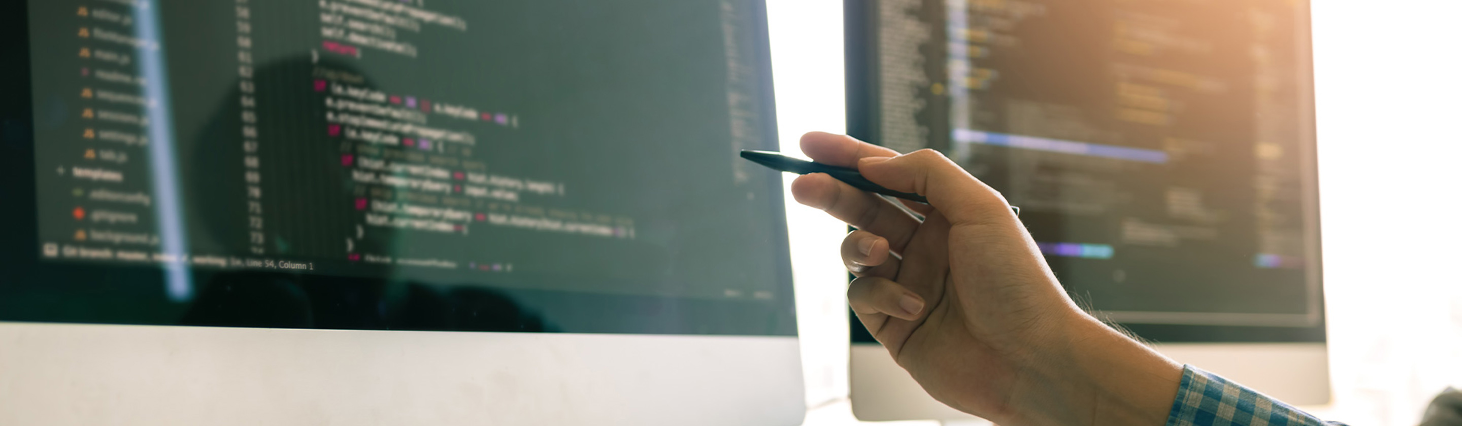 A computer with a coding program open and a person pointing at the work