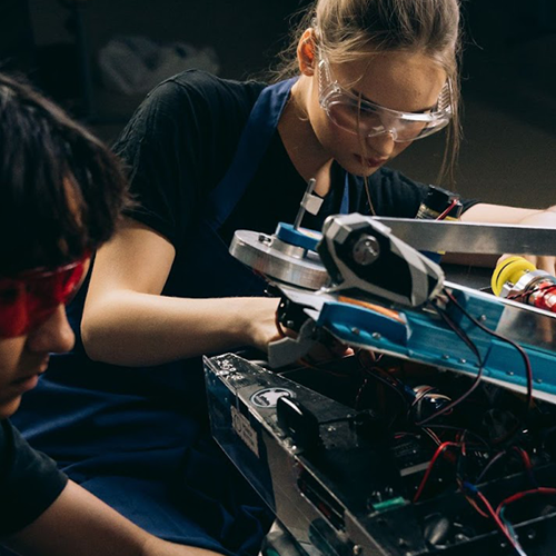 Students wearing safety gear work on a robotics project