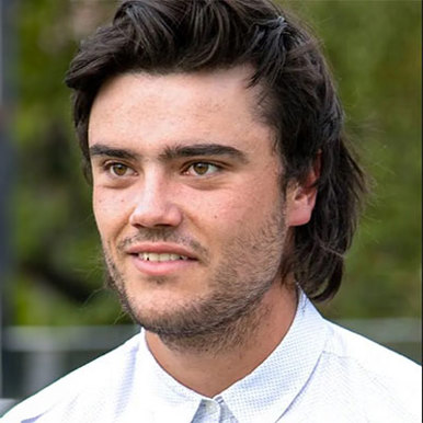 A man with long hair wearing a white shirt looking into the camera