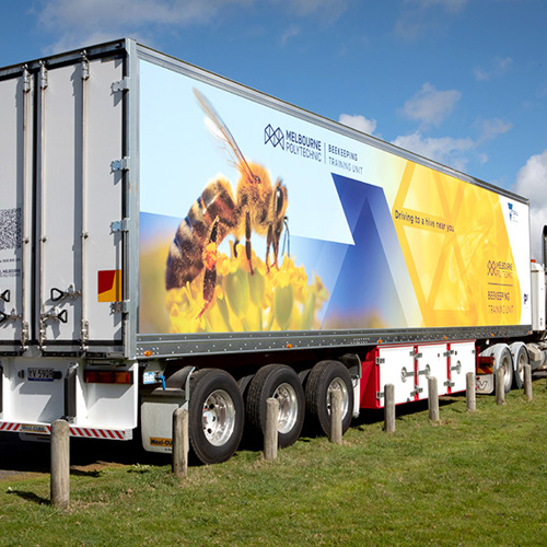 A large truck with "Melbourne Polytechnic Beekeeping Training Unit" and an image of a bee printed on the side.