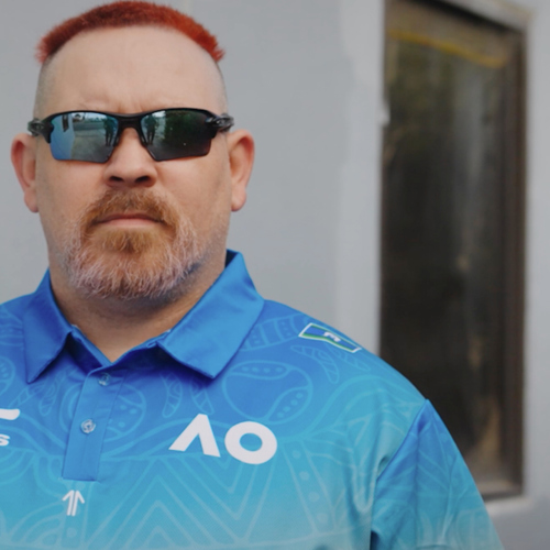 A man wearing sunglasses with dyed red hair and a blue polo shirt.