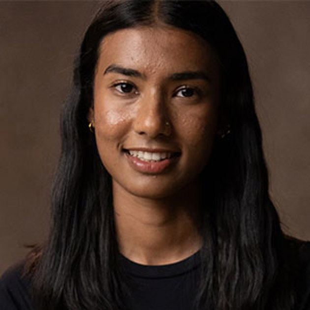 A woman with long black hair and a black shirt smiling at the camera