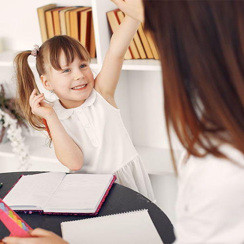 Little girl high-fiving teacher as she completes her homework